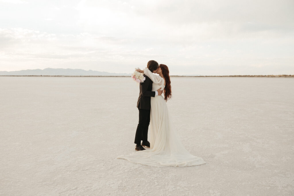 Romantic wedding photography of bride and groom kissing at Bonneville Salt Flats in Utah.