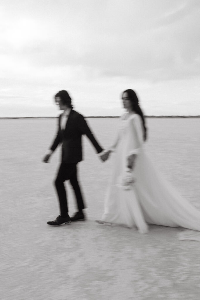 Bride and groom walking during wedding photography at Bonneville Salt Flats in Utah.