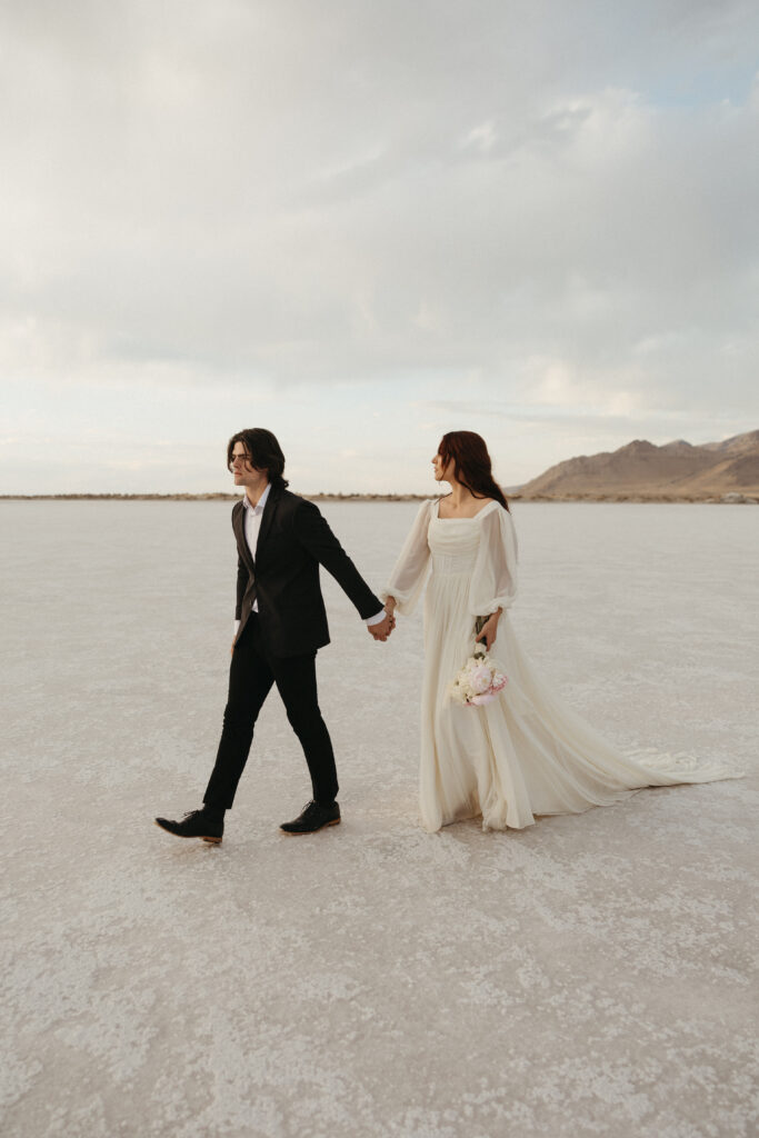 Bride and groom walking during wedding photography at Bonneville Salt Flats in Utah.