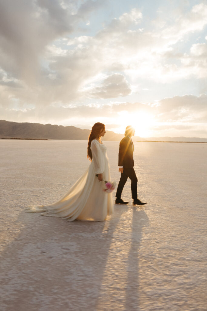 Bride and groom walking at golden hour during elopement at Bonneville Salt Flats in Utah.