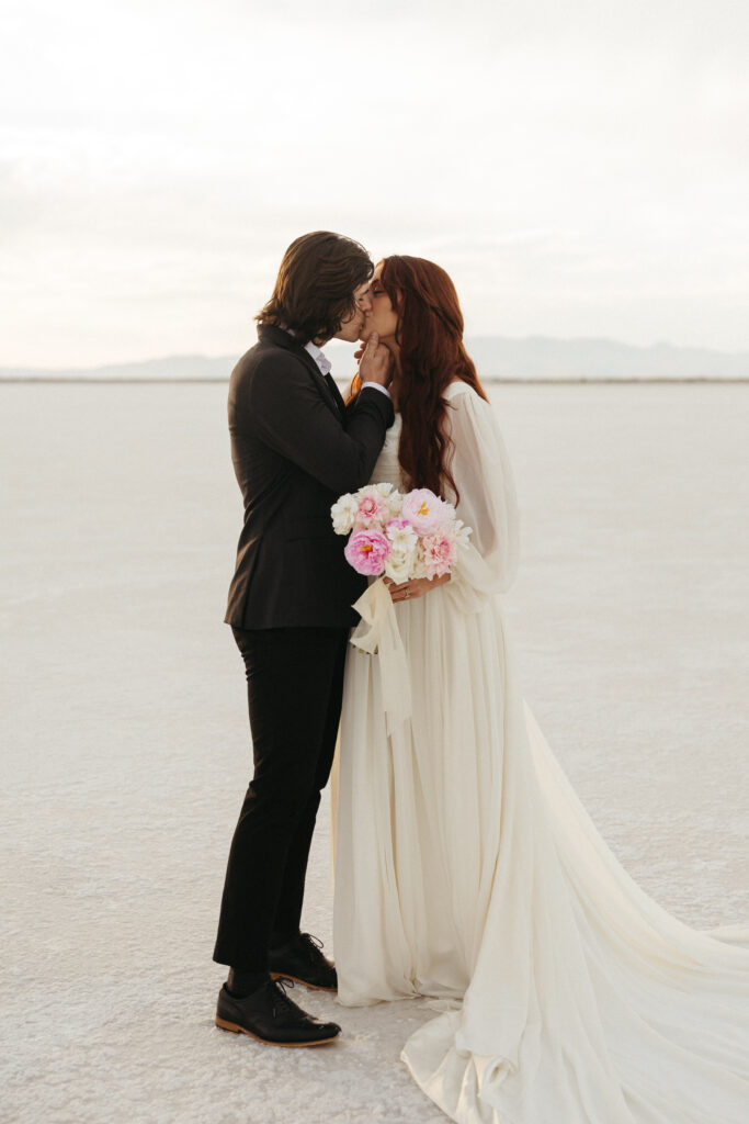 Bride and groom share kiss after eloping at Bonneville Salt Flats in Utah.