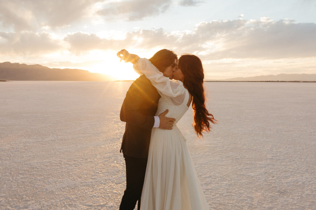 Romantic golden hour kiss between bride and groom during elopement photography at Bonneville Salt Flats in Utah.